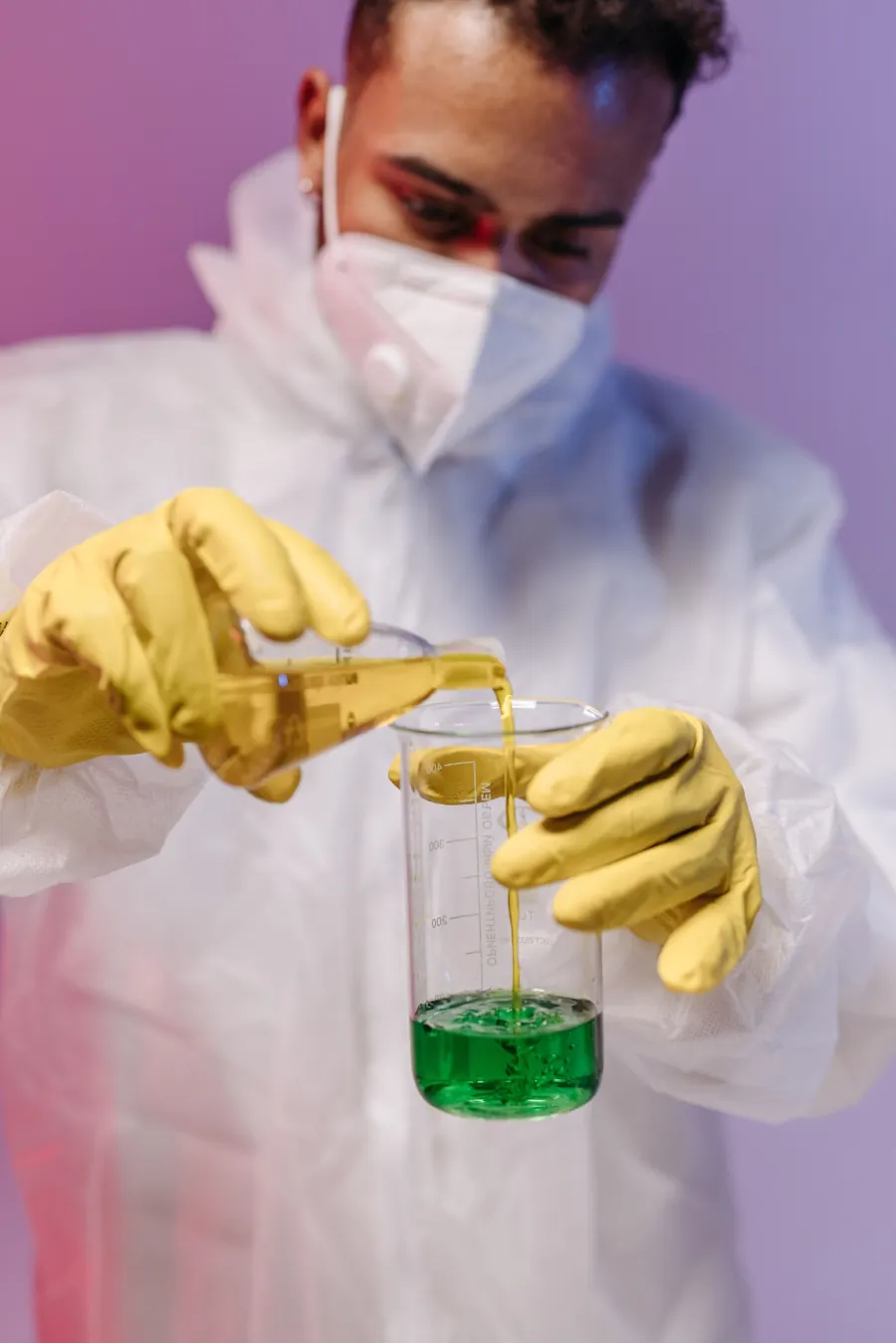Técnico con traje y guantes mezclando un químico verde